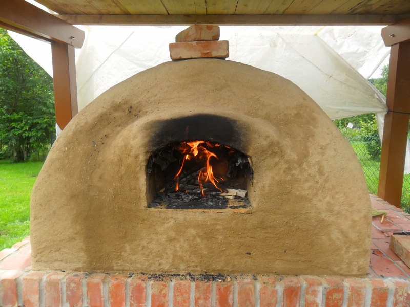 Um das provisorische Dach nicht zu gefährten, habe ich die Öffnung für das Abzugsrohr mit <br />Steinen einstweilen abgedeckt. Deshalb ist der Ofen vorne auch so stark verraucht UND weil ich auch die vordere Schalung ausgebrannt hatte und die Flamen Hochschlugen. Leider war die Plane nicht dicht, was mir später den Schweiss auf die Stirn getrieben hat. Die Hitze tat ihr übriges.