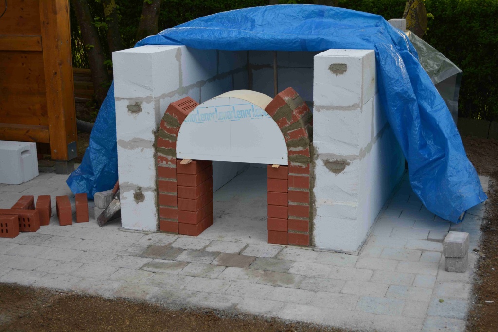 Der Sockel ist gemauert, der Rundbogen aus Klinker am entstehen. Das Wetter erfordert leider des öfteren einen Planeneinsatz.